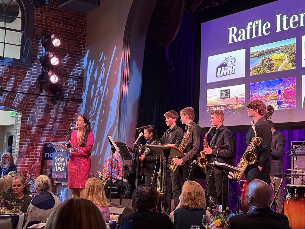speaker on a stage surrounded my musicians